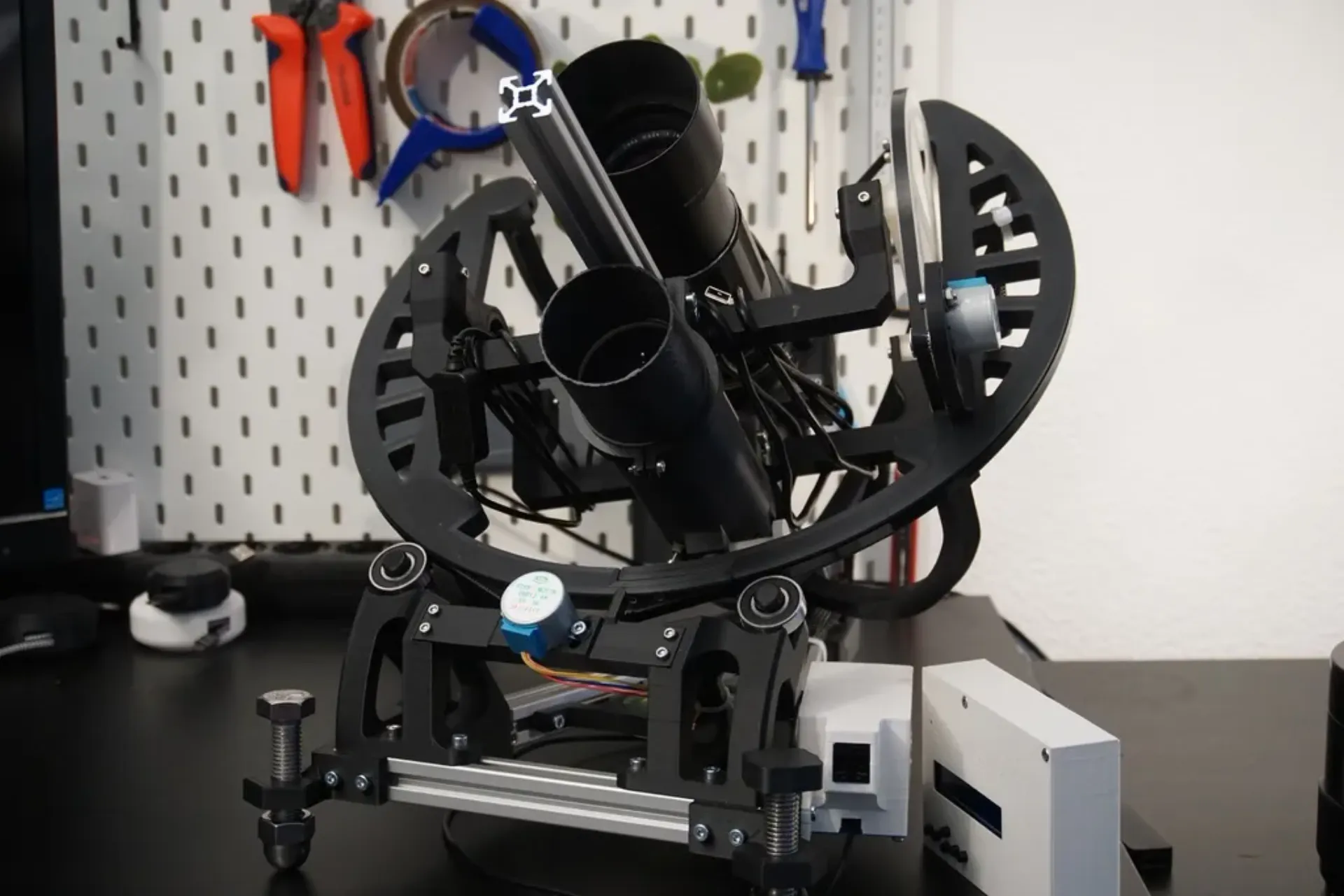 3D-printed OpenAstroTracker astrophotography mount with stepper motors and a camera tube on a workbench